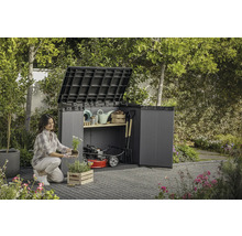 Žena sadí kvety pred otvorenou záhradnou skriňou so záhradným náradím