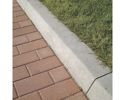 Betónový obrubník cestný 100/20/12 sivá Detail dlažobných dosiek vedľa okraja trávnika.