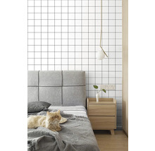 Spálňa s posteľou, nočným stolíkom, lampou a tapetou so štvorcovým vzorom.