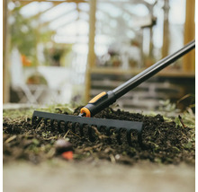 Záhradné hrable používané na záhone so zeminou.