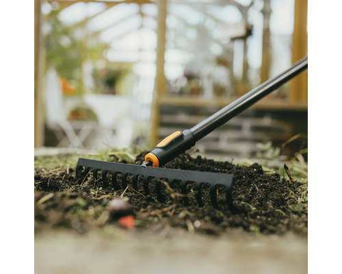 Záhradné hrable používané na záhone so zeminou.