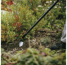 Záhradná motyka používaná v záhone na úpravu pôdy.