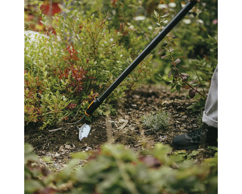 Záhradná motyka používaná v záhone na úpravu pôdy.