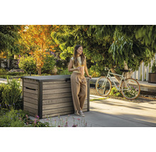 Záhradná scéna so ženou opierajúcou sa o drevený úložný box a držiaci šálku kávy.