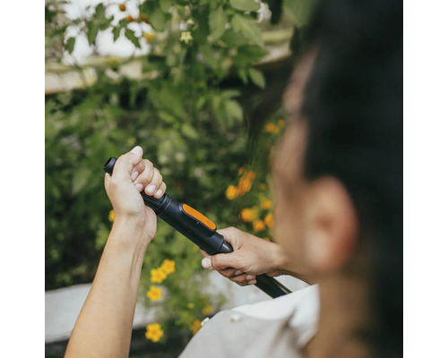 Osoba drží v ruke trysku záhradnej hadice