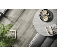 Interiérová fotografia miestnosti s drevenou podlahou, okrúhlym stolom s mramorovou doskou a dekoráciami.