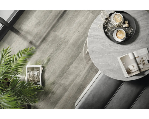 Interiérová fotografia miestnosti s drevenou podlahou, okrúhlym stolom s mramorovou doskou a dekoráciami.