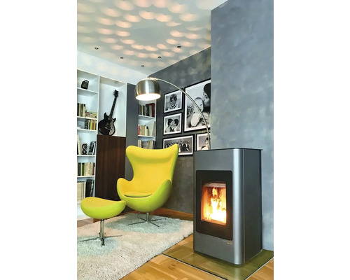 Obývacia izba s krbovými kachľami, kreslom, stojacou lampou a knižnicou