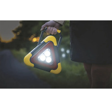 Osoba drží trojuholníkové pracovné svetlo s rukoväťou