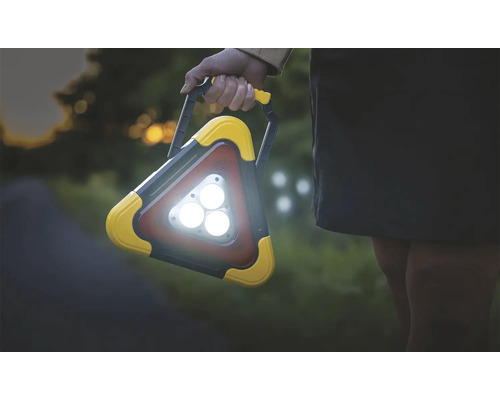 Osoba drží trojuholníkové pracovné svetlo s rukoväťou