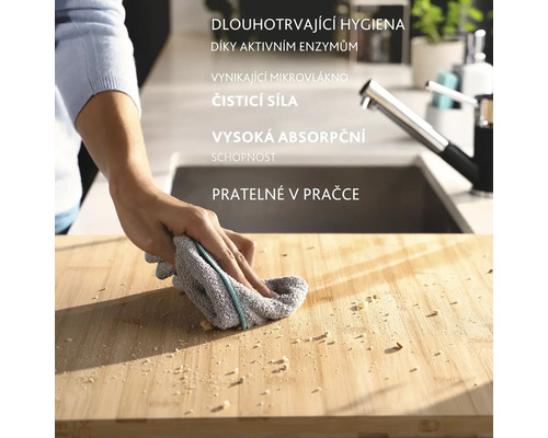 Osoba čistí dosku na krájanie handrou. Handra je sivá s farebným pruhom.