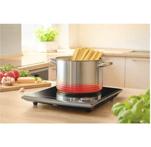 Nerezový hrniec so špagetami na indukčnej varnej doske v kuchyni