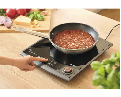 Osoba ovláda indukčný varič Sencor s panvicou s rajskou omáčkou.
