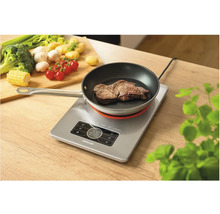 Indukčná varná doska s panvicou a steakom na drevenom stole