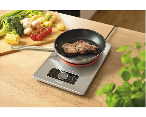 Indukčná varná doska s panvicou a steakom na drevenom stole