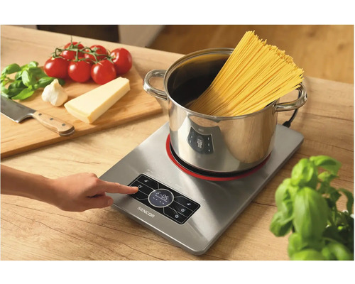 Indukčná varná doska s hrncom, špagetami a prísadami na prípravu jedál
