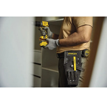 Remeselník s akumulátorovým skrutkovačom, opaskom na náradie a skladacím metrom stavia skriňu