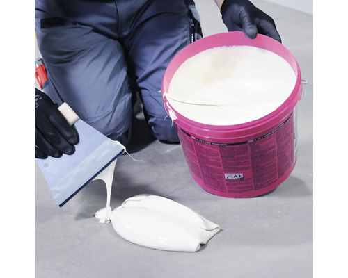 Remeselník so špachtľou a vedrom disperzného lepidla