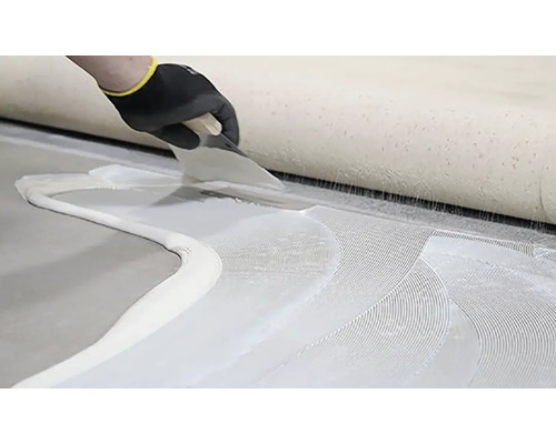 Nanášanie lepidla na podlahovú krytinu pomocou špachtle