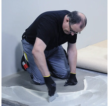 Remeselník nanáša lepidlo na podlahu.