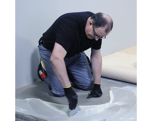 Remeselník nanáša lepidlo na podlahu.