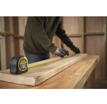 Remeselník značí drevenú dosku pomocou zvinovacieho metra Stanley Fatmax s dĺžkou 8 metrov na pracovnom stole