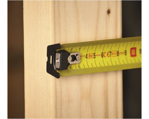 Žltý zvinovací meter s klipom na kuse dreva