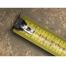 Žltý zvinovací meter s kovovými prvkami na povrchu