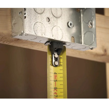 Kovová inštalačná krabica so žltým zvinovacím metrom na meranie na drevenej konštrukcii