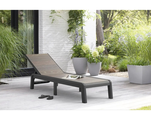 Záhradná scéna so záhradným lehátkom, rastlinami v kvetináčoch a topánkami