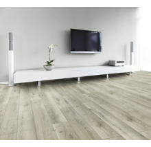 Obývacia izba so svetlou drevenou laminátovou podlahou, bielou nízkou skrinkou, televízorom a reproduktormi