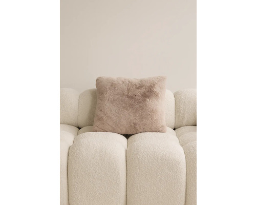 Štvorcový ozdobný vankúš so vzhľadom kožušiny na pohovke.