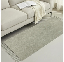 Sivý behúň so strapcami vedľa pohovky s knihou