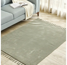 Štvorcový koberec so strapcami vedľa pohovky na drevenej podlahe