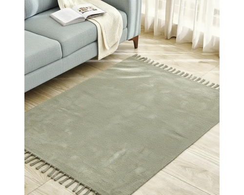 Štvorcový koberec so strapcami vedľa pohovky na drevenej podlahe