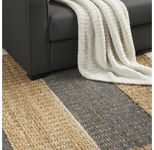 Detailný pohľad na pruhovaný koberec pod pohovkou s dekou.