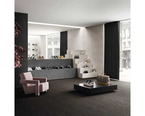 Interiér s kobercom, kreslom a výstavnou plochou pre topánky a doplnky