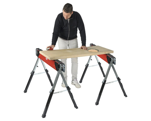 Remeselník brúsi drevenú dosku na dvoch kozách