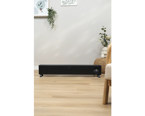 Čierny konvektorový ohrievač v obývacej izbe na drevenej podlahe