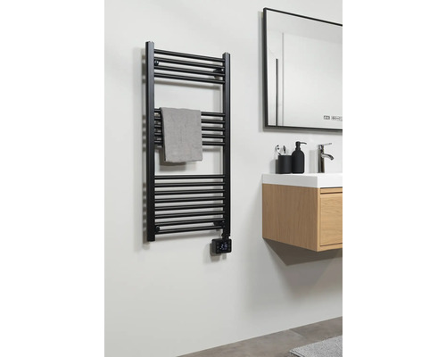 Čierny ohrievač uterákov s uterákom v kúpeľni