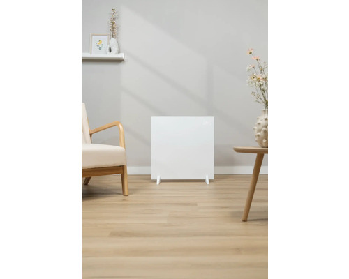 Biely radiátor v obývacej izbe vedľa kresla a príručného stolíka.