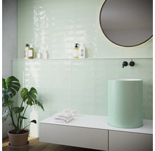 Moderná kúpeľňa s mätovo zelenými obkladmi, umývadlom na dosku a okrúhlym zrkadlom