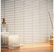 Scéna s bielymi, podlhovastými obkladačkami, dávkovačom mydla, sviečkou a uterákom na drevenom stole