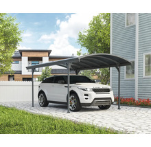 Auto pod prístreškom pre auto na dláždenej príjazdovej ceste pred domom