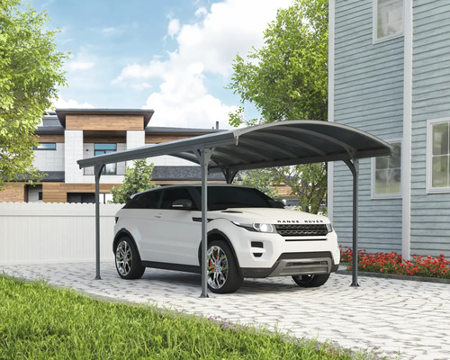 Auto pod prístreškom pre auto na dláždenej príjazdovej ceste pred domom