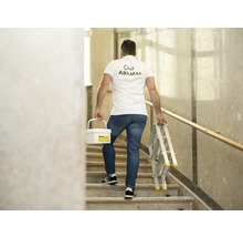 Muž nesie vedro s farbou a rebrík po schodoch