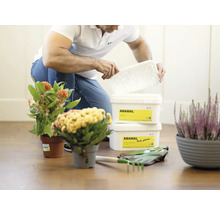 Osoba otvára nádobu s prípravkom na ochranu rastlín Abamal v záhradnom prostredí