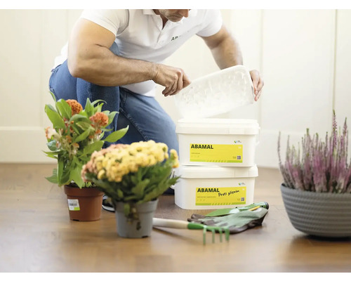 Osoba otvára nádobu s prípravkom na ochranu rastlín Abamal v záhradnom prostredí