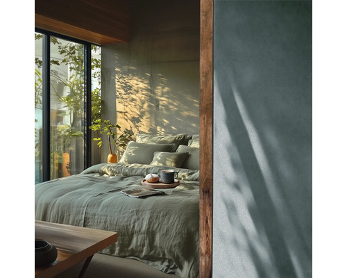 Spálňa s posteľou, vankúšmi, prikrývkou a rastlinami vedľa okna