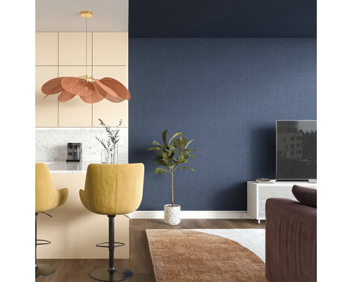 Obývacia izba s modrou tapetou, barovými stoličkami a izbovou rastlinou